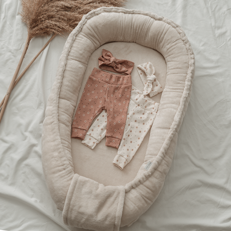 Babynestje van bamboekatoen in de kleur sand met een babybroekje en twee haarbandjes erin